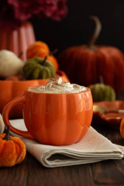 Sonbahar dekoruyla çevrili, krem şanti ve baharatlı balkabaklı latte..