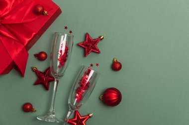 Şampanya Kadehleri, Hediye Kutusu ve Yeşil Arkaplanda Kırmızı Noel Süslemeleri