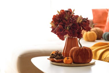 Sehpası, balkabağı ve çiçek aranjmanı olan Şükran Günü oturma odası dekoru..