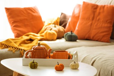 Balkabağı, çaydanlık, çay fincanı ve rahat battaniyeli sonbahar oturma odası dekoru..