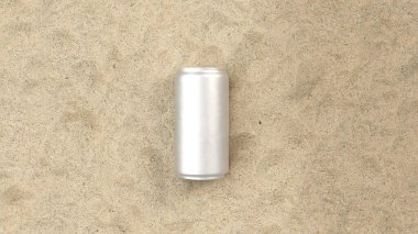 Plajda kumun üzerinde beyaz metal bir alüminyum soda kutusu.