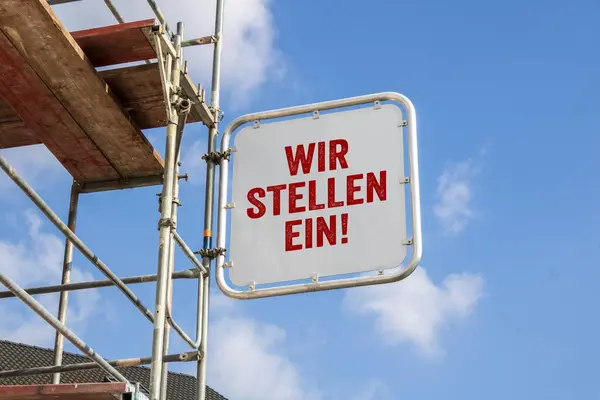 stock image House with scaffolding with blue sky background with big sign and german letters for we are hiring - wir stellen ein