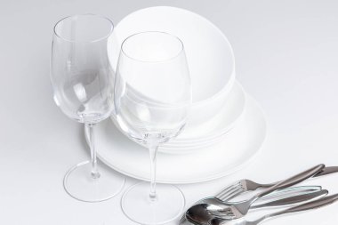 Beyaz arkaplanda çatal bıçak takımı olan boş bardaklar