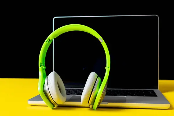 Masada siyah ekranlı modern kulaklıklar ve dizüstü bilgisayar.