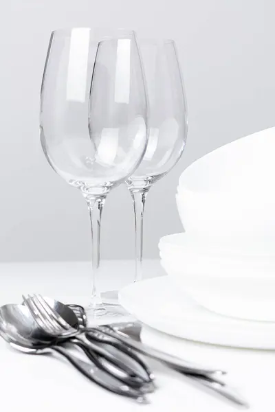 Beyaz arkaplanda çatal bıçak takımı olan boş bardaklar