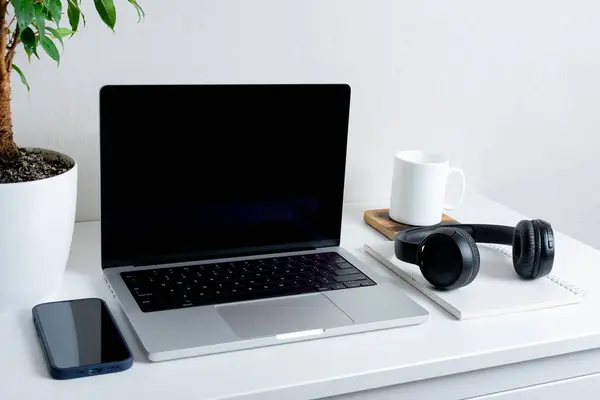 Siyah ekranlı bilgisayar, yeşil bitki, akıllı telefon, kulaklık ve bardak. Merkez ofis kavramı..