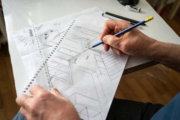 male architect drawing on a piece of paper, top view of a hand with a pencil and a ruler