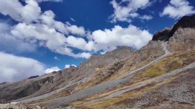 4K Dağ Manzarası Cephesi ve Yana Dönen Manzara Beton Yol boyunca, Günışığı Yeşil Dağları Aydınlatıyor, Tepelerde Dramatik Karanlık Işık, ve Karanlık ve Beyaz Bulutlar Arasında Güneş Parlıyor,
