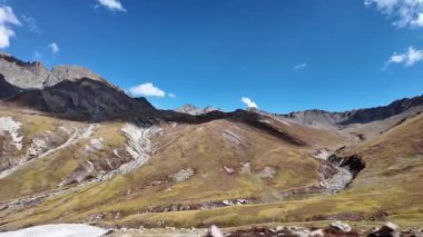 4K Dağ manzarası Güzel Yeşil Dağ Dağları, Gölgede Bazı Parçalar, Çoğunlukla Güneş Işığı Altında Banyo, ve Yumuşak Sinema Bulutlarıyla Çarpıcı Mavi Gökyüzü.