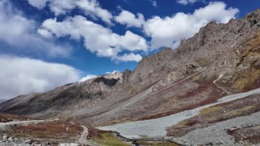 4K Dağ Manzarası Yanı başında akan bir nehir, Sunlit Yeşil Dağları, Tepelerdeki dramatik gölgeler, Karanlık ve Beyaz Bulutlar Arasında parlayan Güneş
