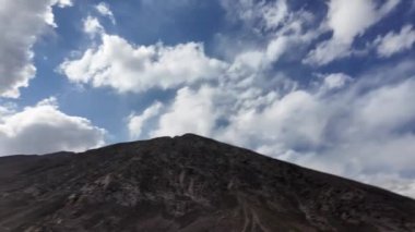 Dark Peaks, Rocky Outcrops, Grass Patches ile Majestic Mountain Range 'ın sinematik yan görüntüsü. Aşağıda, Wding Black Bitumen Yolu Derin Vadi' ye çıkıyor.