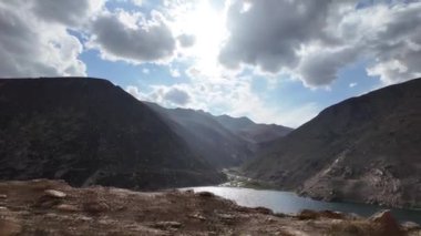 Derin Yeşil Göl 'ün Sinema Perspektifi, Karanlık Dağlar tarafından çerçevelenmiş, bir yol kenarından görülen, Mavi ve Yumuşak Bulutlar, Kara Bulutlar ve Hafif Yağmur Damlaları ile dramatik bir gökyüzü altında,