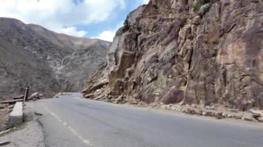 Kara Bitumen Yolu, Rocky Dağı 'nın yanı sıra, Koyu Yeşil Suyla Güzel Göl, Arka planda Görkemli Dağ Sırası, Hafif Yağmur Damlaları, Yumuşak Bulutlu Mavi Gökyüzü