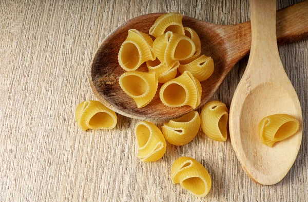 uncooked pasta in wooden spoon