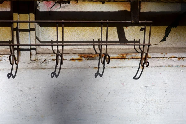 old metal clothes hanger hanging on old concrete wall