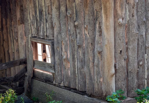 A close up corner view of an old vertical style log barn with a broken out window. Makes a nice rustic country scene.