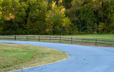 Huzurlu bir asfalt yol, küçük bir ağaçlık çayırın etrafında kıvrılır. Kırsal ahşap çitler Arkansas 'taki sükunete hoş geldin daveti sunuyor gibi görünüyor..