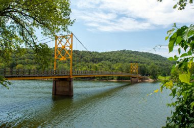 Köşelerdeki yeşil yapraklar, izleyiciyi Arkansas 'ta açık ve güzel bir günde Beyaz Nehir üzerindeki tek yönlü asma köprüye yönlendiriyor. Mimarlık ve doğa birleşir..