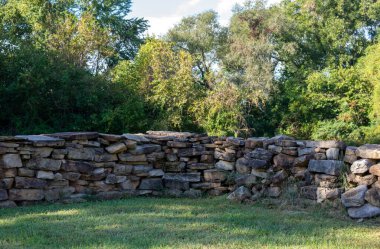 Yakından bak, arka planda yeşil ağaçlar ve ön planda yeşil çimenler olan bir kaya duvarının köşesine bak..