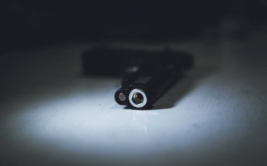 Crime scene, gun on the table with very little light