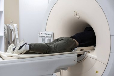 MRI (magnetic resonance imaging) scanner in a hospital, with patient being scanned and diagnosed. Modern medical equipment, medicine and health care concept. clipart