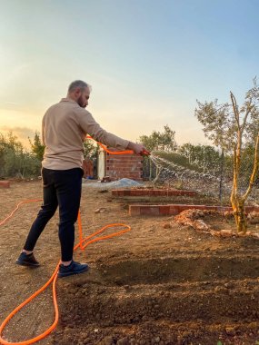 Bahçedeki çimleri sulayan bir bahçıvan.
