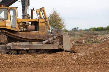 Dozer working at construction site. Bulldozer for land clearing, grading, utility trenching and foundation digging. Crawler tractor and earth-moving equipment.