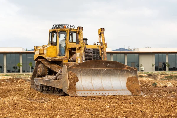 Dozer working at construction site. Bulldozer for land clearing, grading, utility trenching and foundation digging. Crawler tractor and earth-moving equipment.