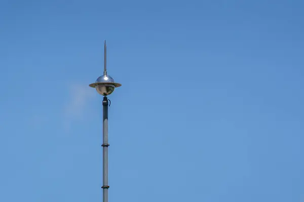 Mavi gökyüzüne karşı bir binanın çatısında paratoner var. Yıldırım çarpması