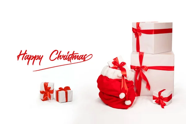 圣诞卡上圣诞老人的手提包和其他圣诞礼物放在一起 礼品盒用白纸包裹 用红丝带装饰 白色背景的节日横幅 上面印有 圣诞快乐 — 图库照片