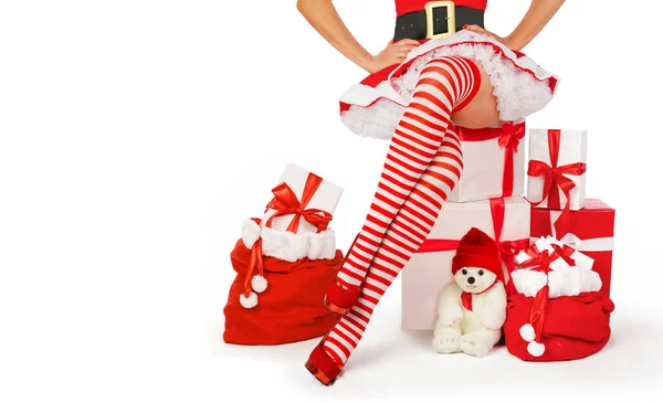 性感的圣诞老人 女人的腿和圣诞礼物 漂亮的性感女人 穿着圣诞老人服装 长腿长袜 脚上有条纹 脚跟是红色的 带有复制空间的白色背景 — 图库照片