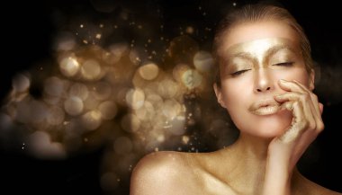 Altın bazlı yaşlanma karşıtı cilt bakımı. Altın işlemeli güzel bir kadın. Kapalı gözlerle poz veriyor ve altın rengi arka planda sakin bir ifade sergiliyor.