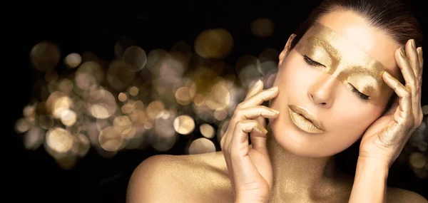 Gold based skincare concept. Beauty spa woman face with gold mask on eyes, neck and lips holding her hands gracefully by the sides of face with closed eyes in a sensual gesture.