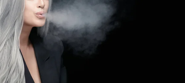 Cropped view of a beautiful smoker female. Silver haired woman blowing smoke cloud in a panorama banner isolated on black background with copy space