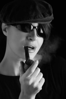 Beauty smoking a pipe. Stylish brunette woman with a vintage wooden pipe. Monochrome studio portrait over black background