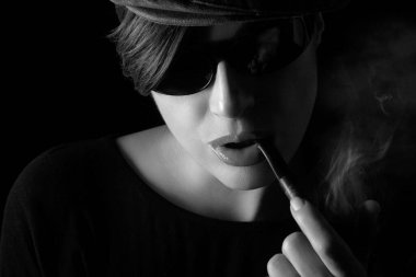 Woman smoking pipe. Monochrome closeup studio portrait isolated on black background with copyspace
