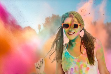 Gökkuşağı renkli tozla kaplı kaygısız neşeli kadın Holi renk festivalini kutluyor. Genç bir kadın açık havada renkli tozla eğleniyor. Kopyalama alanı olan yakın plan portresi
