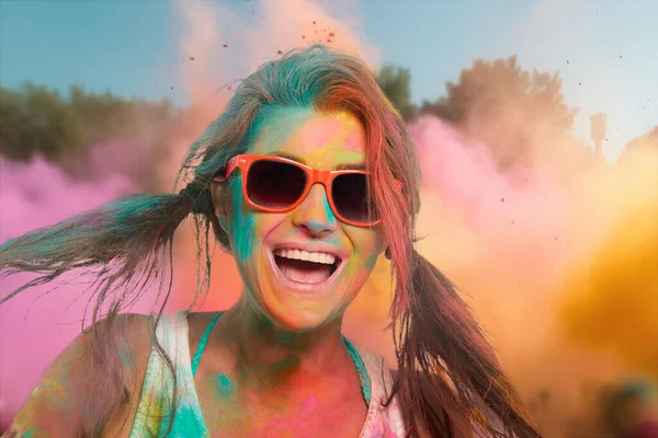 Gökkuşağı renkli tozla kaplı kaygısız neşeli kadın Holi renk festivalini kutluyor. Genç bir kadın açık havada renkli tozla eğleniyor. Kopyalama alanı olan yakın plan portresi