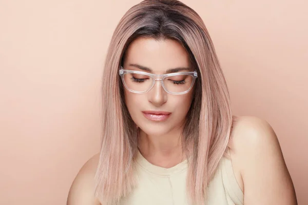 ピンクの髪とクリア縁のメガネを持つファッショナブルな女性でほこりっぽいパステルピンクの背景にコピースペース — ストック写真