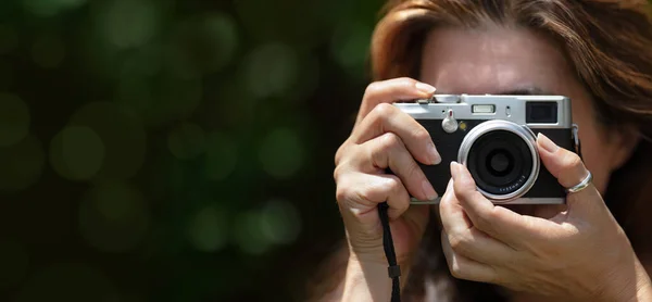 A woman taking pictures with a compact camera outdoors. Traveling and photographing concept. Close-up panorama banner with copy space