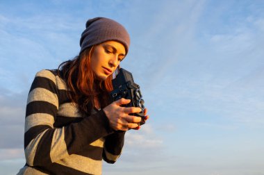 Elinde antika fotoğraf makinesi olan bir kadın fotoğraf çekmeye odaklanıyor..