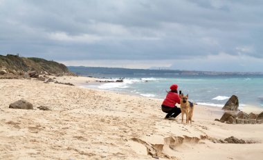 Bir kadın, kumlu bir plajı, denizi ve açık bir gökyüzü olan kıyı manzarasını yakalar. Metin ya da grafik eklemek için telif alanı ile.