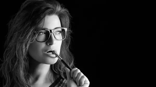Young adult woman in black and white glasses against a black background with copy space.