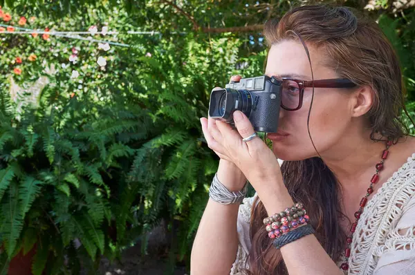 Kobieta Zewnątrz Trzyma Aparat Fotograficzny Fotografujący Roślinę Zaangażowana Swoją Pracę — Zdjęcie stockowe