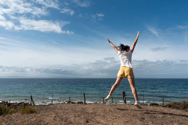 Mujer Segura Salta Aire Libre Orilla Del Océano Capturando Momento Imagen De Stock