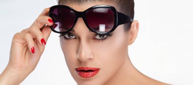 Zarif bir kadın büyük siyah güneş gözlüğü takıyor, güzellik ve yüksek moda sergiliyor. Kırmızı dudaklar ve manikür cazibesini arttırıyor. Güzellik ve moda kavramları için ideal. Beyaz arkaplanda izole.