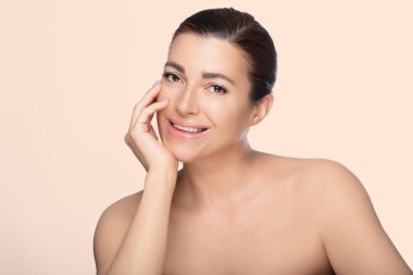 Gülümseyen orta yaşlı kadın doğal güzellik ve cilt bakımı sergiliyor. Bir stüdyo çekiminde zarafet ve sağlığı yakalamak. Yumuşak bir arkaplanda izole edilmiş.