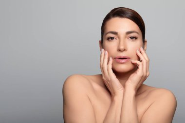 Cilt bakımı için poz veren orta yaşlı güzel bir kadın. Güzellik ve cilt bakımı. Kopyalama alanı olan gri bir arkaplanda izole edilmiş.