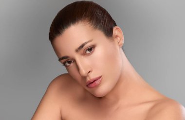 Zarif ten renginde zarif bir kadın, güzellik ve cilt bakımını temsil ediyor. Tarafsız arkaplan, onun doğal zarafetini vurgulayarak kopyalama alanı sağlar.