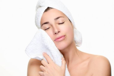 Huzurlu bir kadın cilt bakım rutinini benimser. Yenilenme için yumuşak bir havlu kullanır. Görüntü rahatlama ve kendine bakmanı sağlar. Geniş kopya alanı olan beyaz bir arkaplanda izole edilmiş.